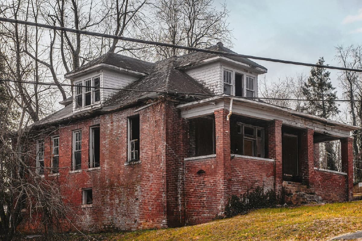 A run-down red brick house under a grey sky