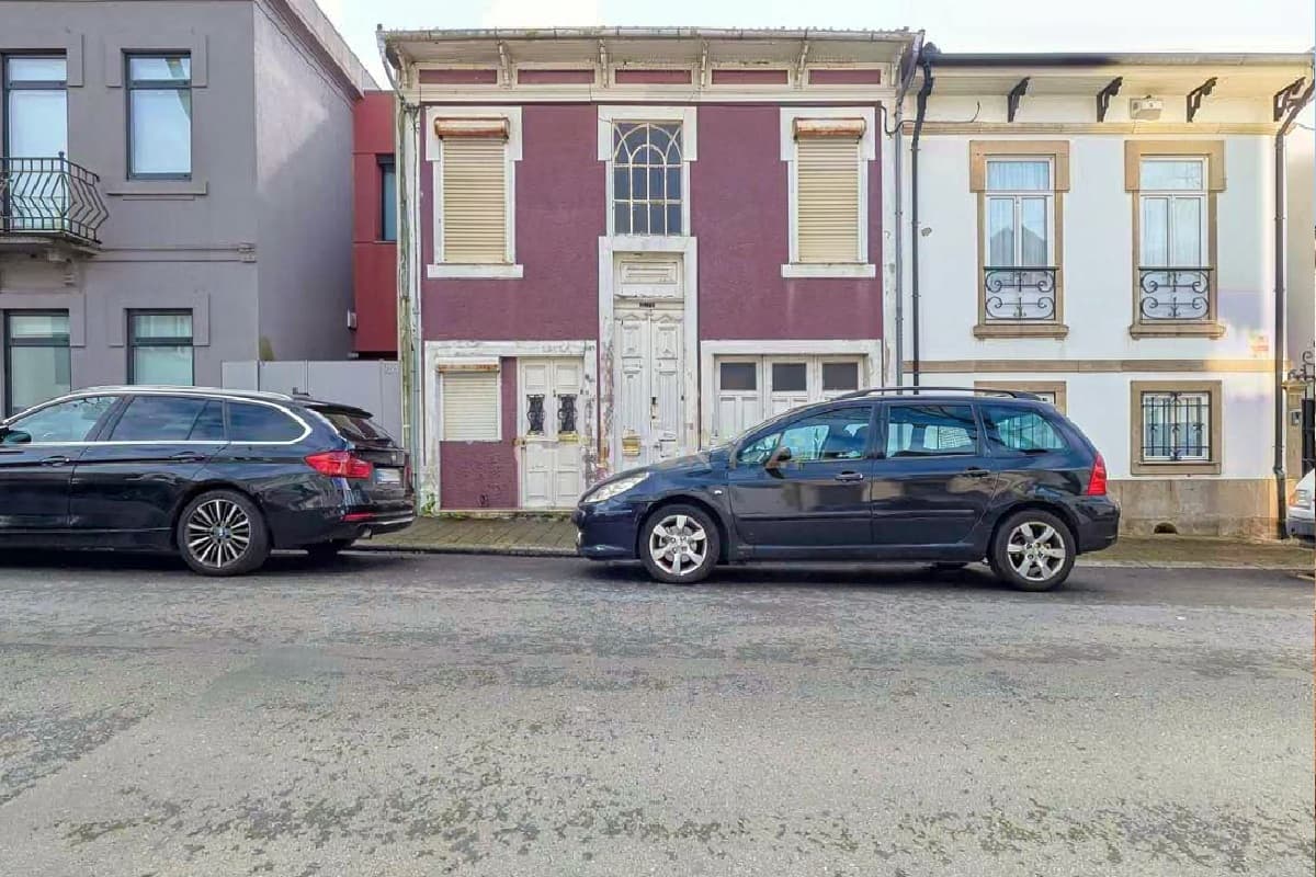 A house front on a street with two parked cars in front of it