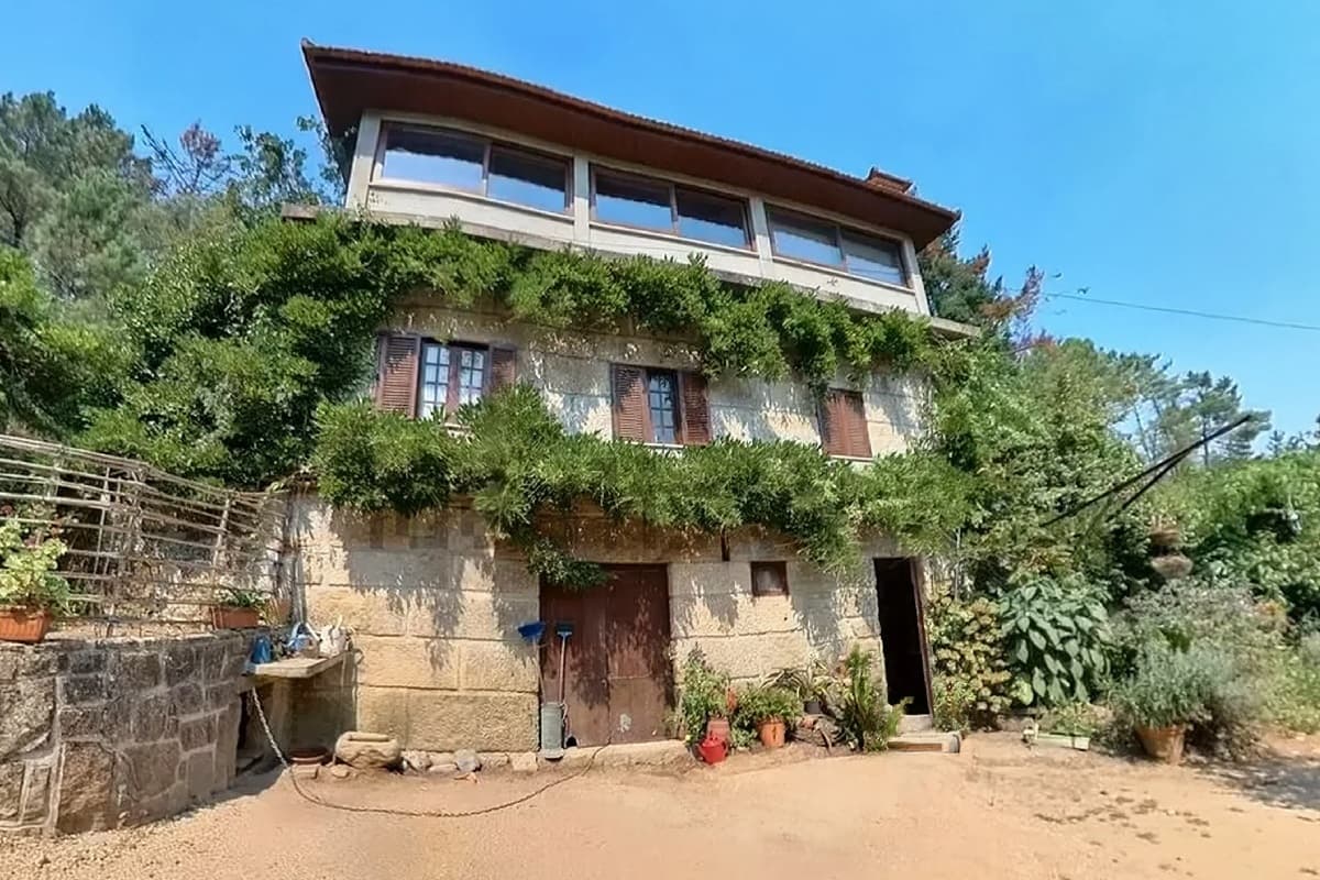 A stone house shot wide-angle from low down, with a curved, leaning frame